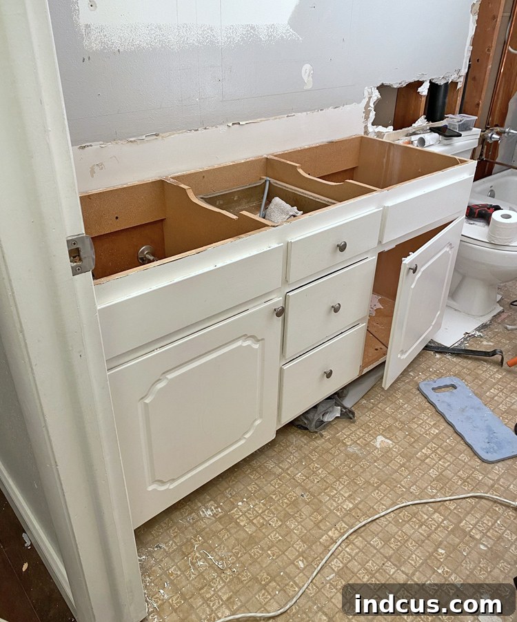 Demolished bathroom space with old vanity removed, showing exposed walls and floor