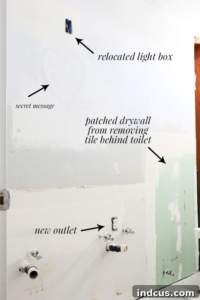 Wall area prepped for new vanity and light fixture, showing drywall patching and electrical adjustments