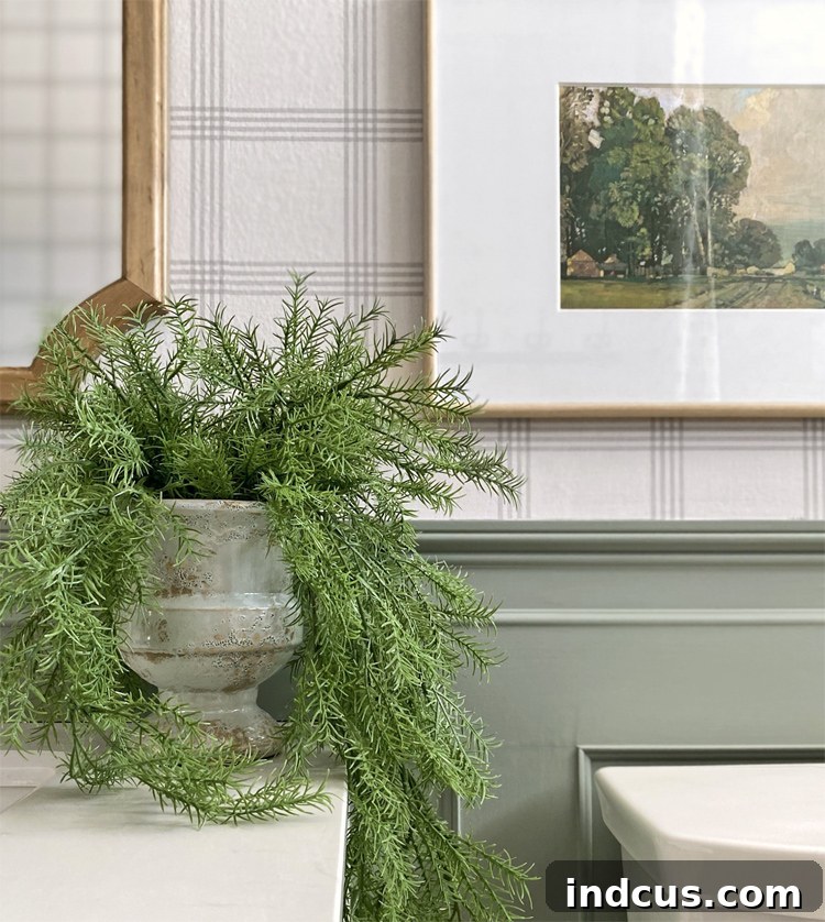 Styling elements in the new bathroom, including old art in a modern frame and a houseplant in a weathered urn