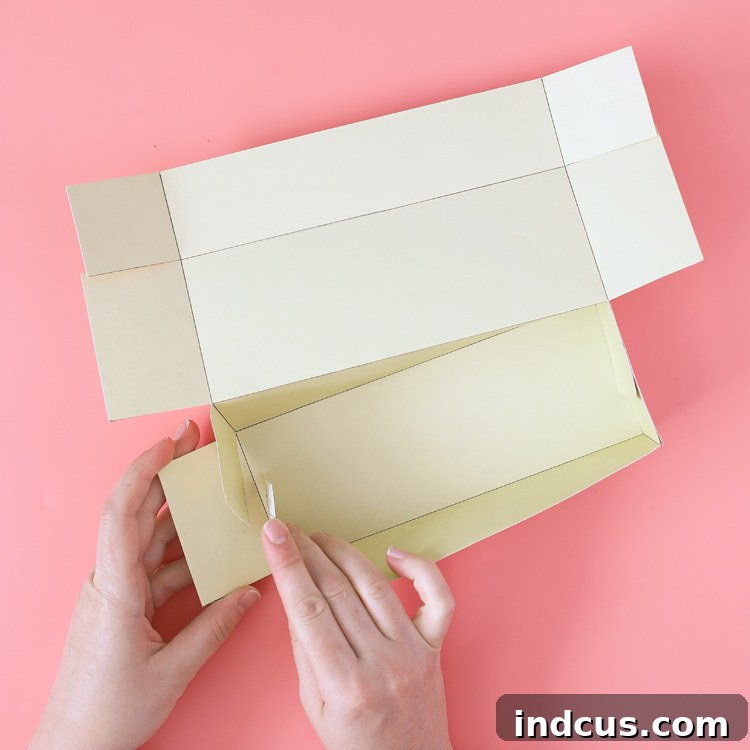 Tutorial step: assembling the base of a paper box by folding and pressing tabs
