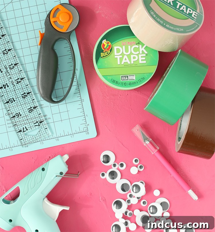 Materials laid out for making Duck Tape ice pop holders: various colors of Duck Tape, rotary cutter, ruler, cutting mat, hot glue gun, glue sticks, craft blade, googly eyes