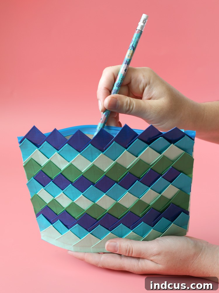 Close-up of a handmade Duck Tape zip pouch featuring a vibrant, textured dragon scale pattern in shades of blue and purple.
