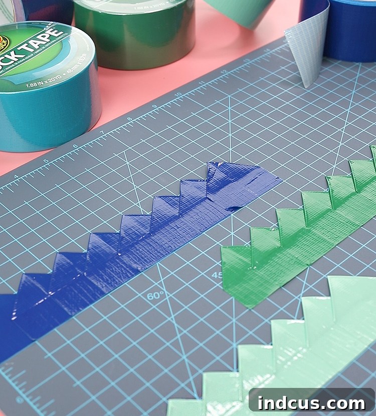 A sequence of seven 'house' shaped Duck Tape pieces layered and offset by 1 inch, forming a continuous strip of dragon scales.