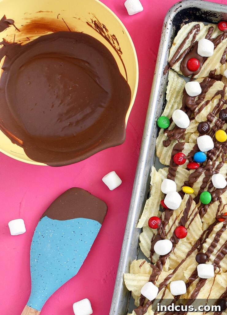 Melted chocolate generously drizzled over a layer of crispy potato chips on a baking sheet, ready for toppings