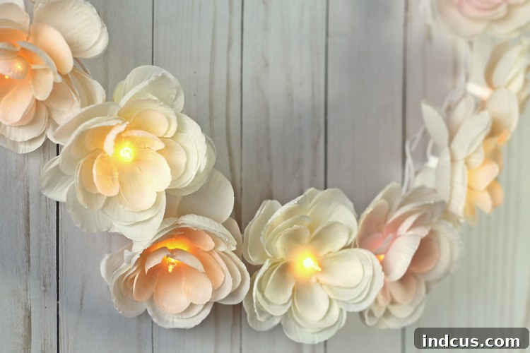 Beautifully crafted DIY lighted floral garland featuring delicate silk ranunculus with warm, twinkling lights peeking from their centers, creating a magical glow.