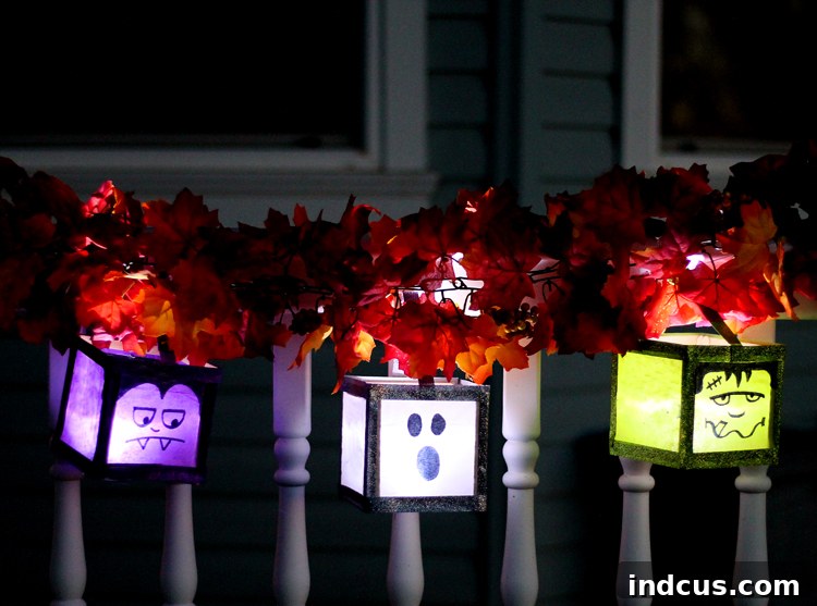 Close-up of three glowing monster luminaries made from craft sticks and tissue paper, set against a dark background.
