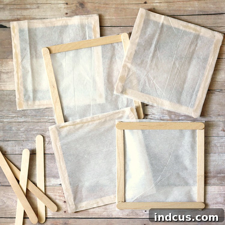 A single tissue paper square with wooden craft sticks glued along all four edges, forming a framed panel.