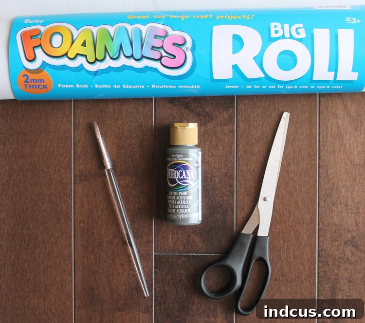 Essential craft supplies laid out, including a roll of EVA craft foam, scissors, paint, and a brush, ready for creating DIY aspen tree wall art.