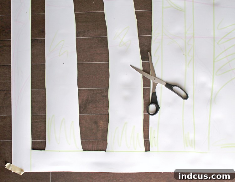 The backside of a large craft foam sheet with aspen tree designs sketched and partially cut out, showing the wide border for stability.