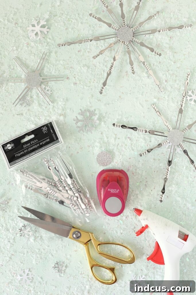 Essential materials for making cocktail fork snowflakes, including forks, cardstock, circle punch, scissors, and hot glue gun.