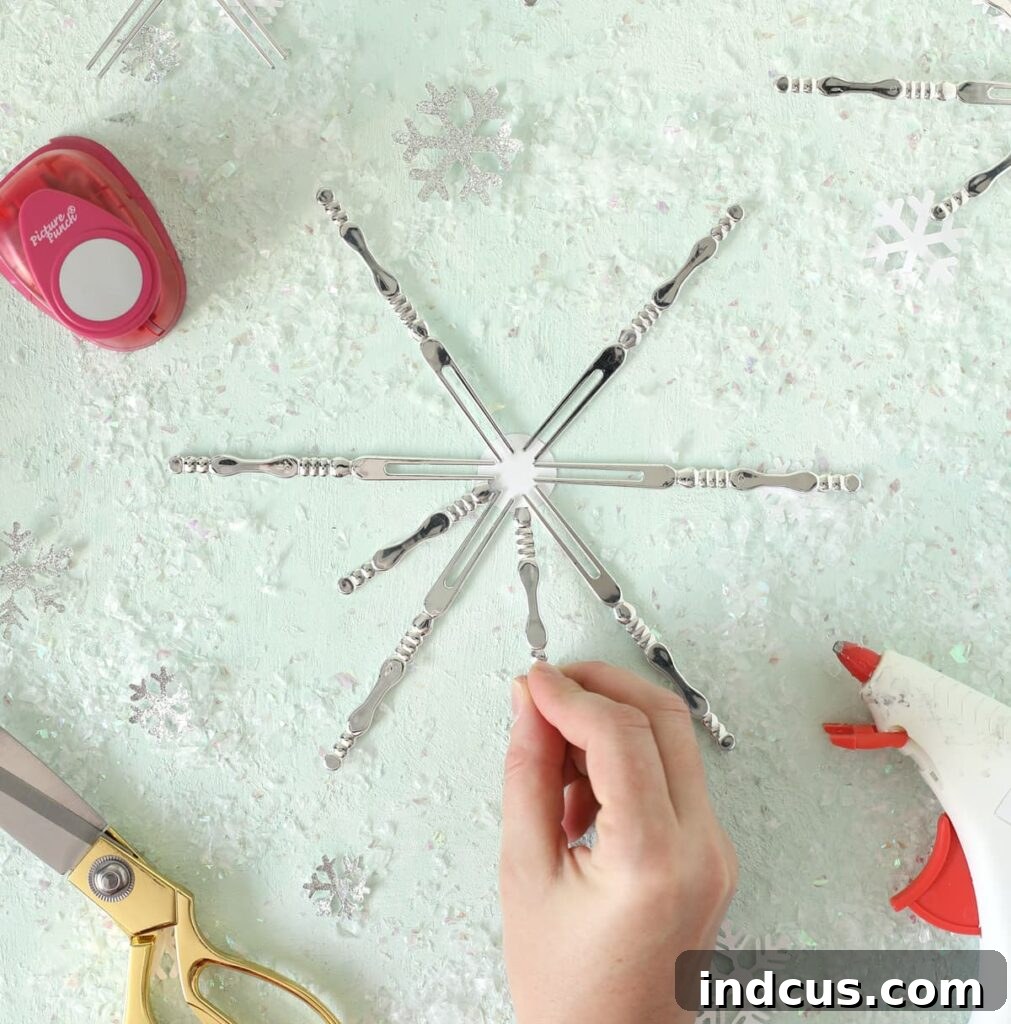 Arranging appetizer forks into a snowflake pattern on a cardstock circle, demonstrating the initial design step.