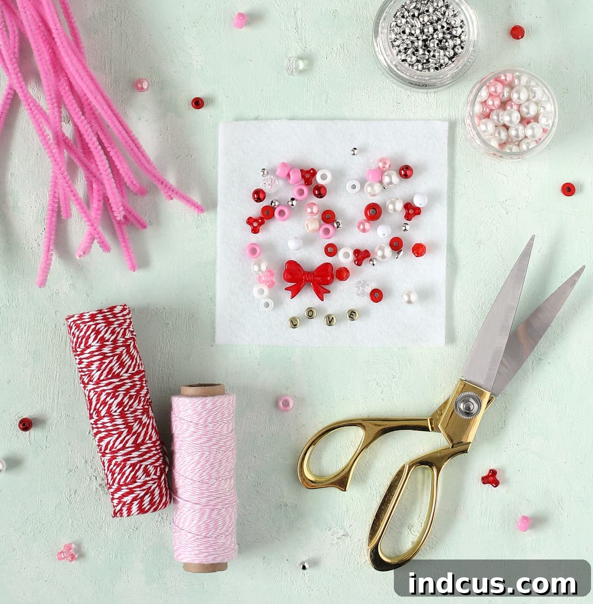 Essential materials for making beaded chenille stem hearts: pipe cleaners, assorted beads, and scissors.