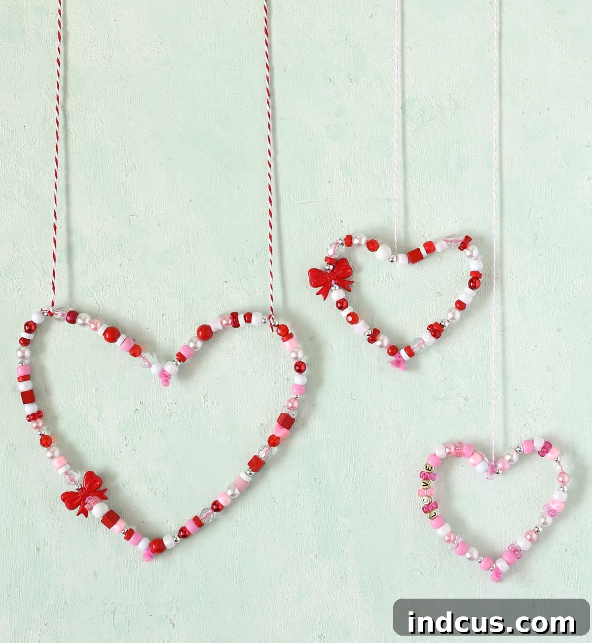 Collection of colorful beaded hearts hanging in a window as a Valentine's Day decoration.