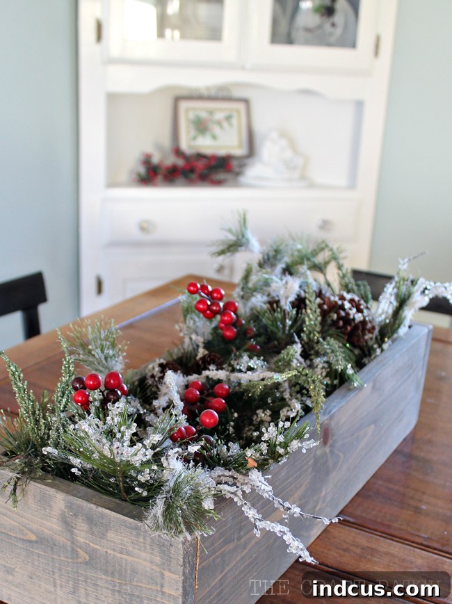 Our Christmas Wonderland 11 Frosted pine and berries Christmas garland elegantly displayed in a wooden trough box on the dining table.