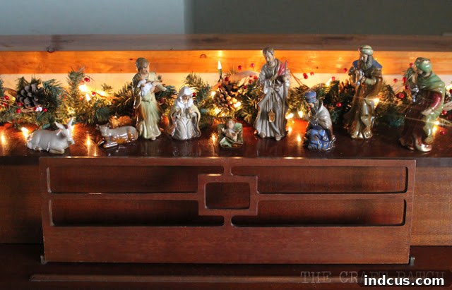 Our Christmas Wonderland 8 Nativity set elegantly displayed on top of the piano, accented with a festive berry and pine cone garland.