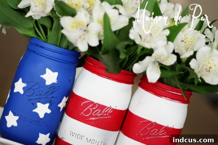 Mason jars painted like American flags, holding utensils and flowers