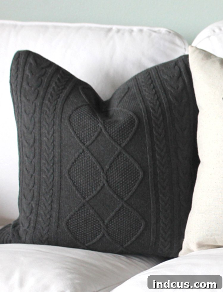 Close-up of a grey cable knit sweater repurposed into a cozy pillow cover, showcasing its rich texture.