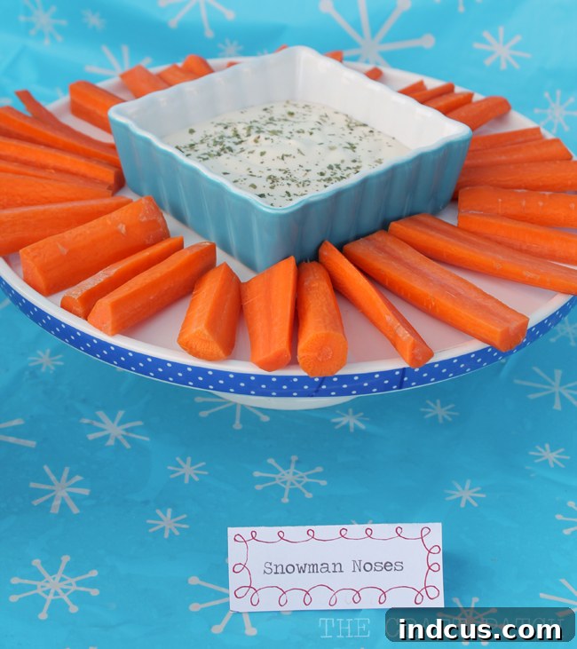 Fresh carrot sticks and creamy ranch dressing, creatively presented as 'Snowman Noses,' a fun and healthy party food for a snowman theme.