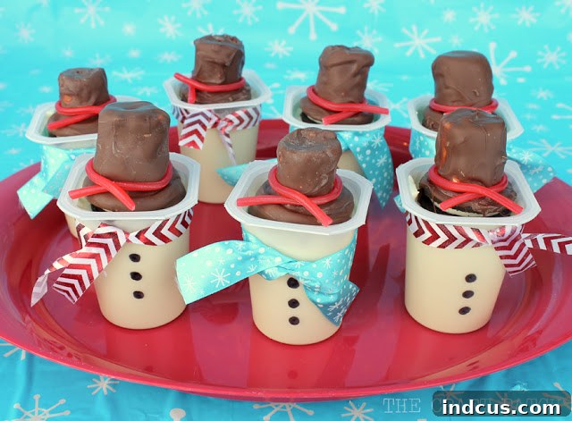 Creative snowman pudding cups, beautifully decorated with festive ribbon, hand-drawn buttons, and topped with edible Oreo top hats.