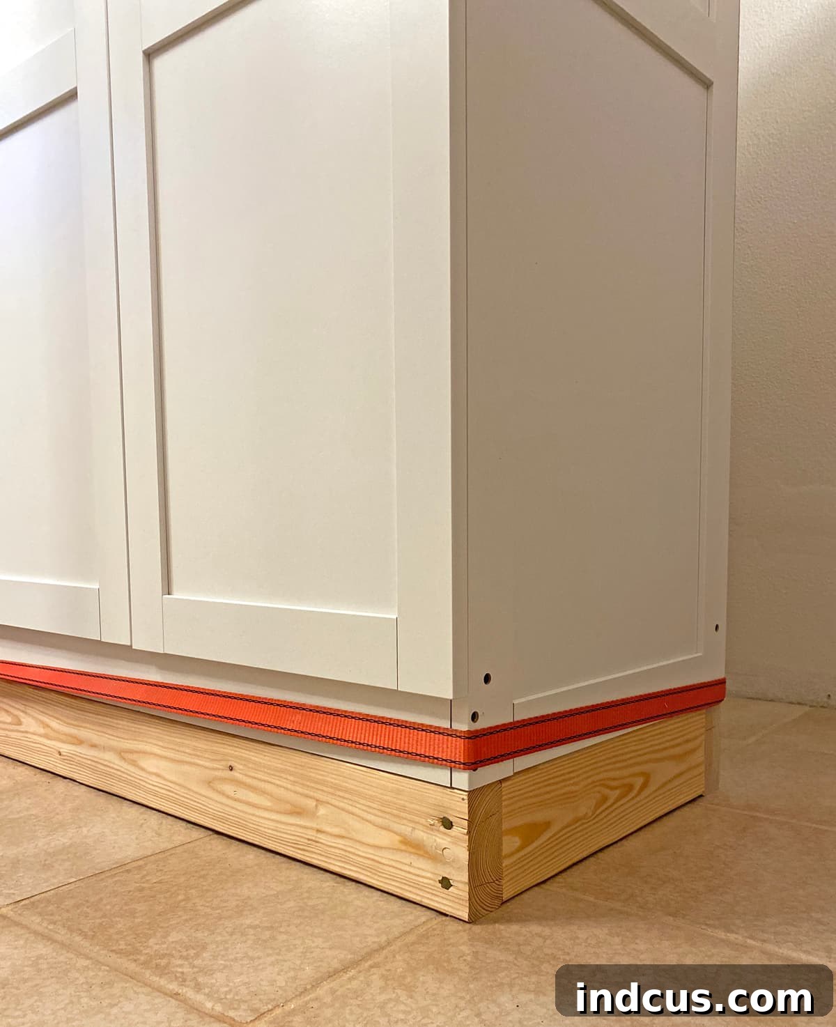 Using a cam strap to tightly pull together multiple DIY built-in cabinets on a base
