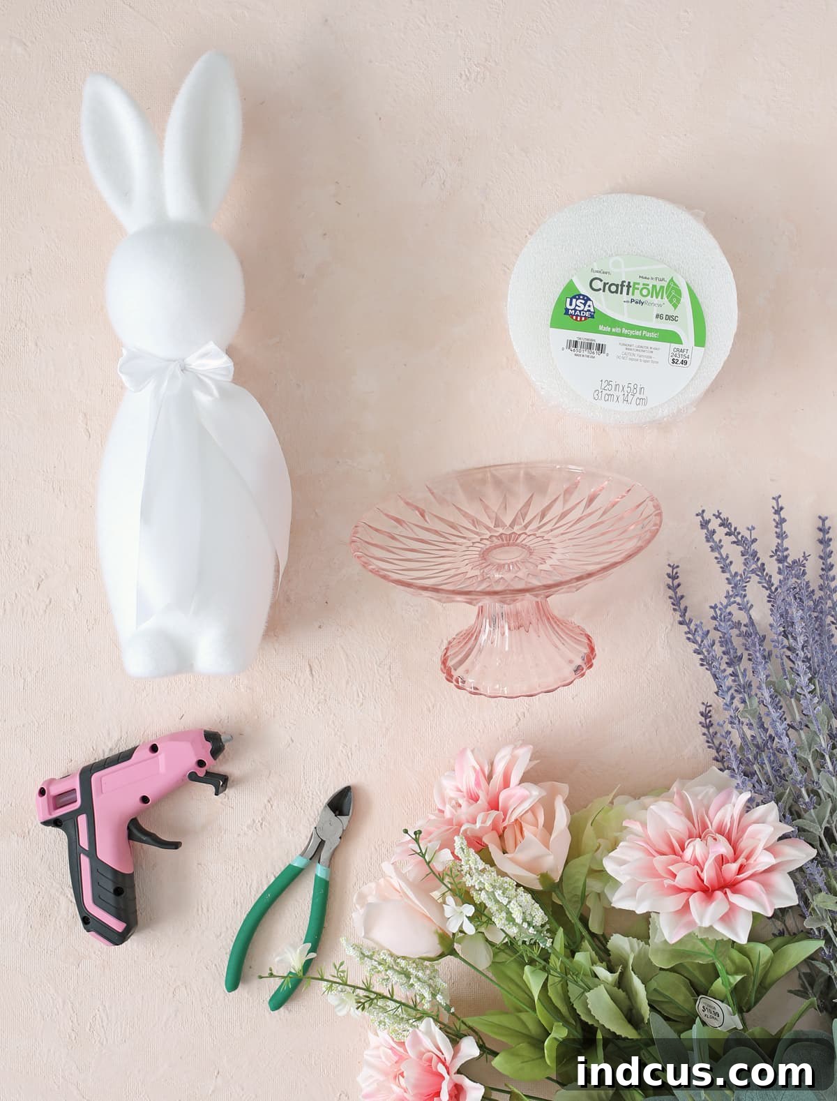 Materials needed for a beautiful spring floral centerpiece, including bunny, cake stand, craft foam, and assorted flowers