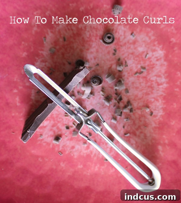 Detailed close-up of the technique for making delicate chocolate curls using a vegetable peeler on a chocolate bar