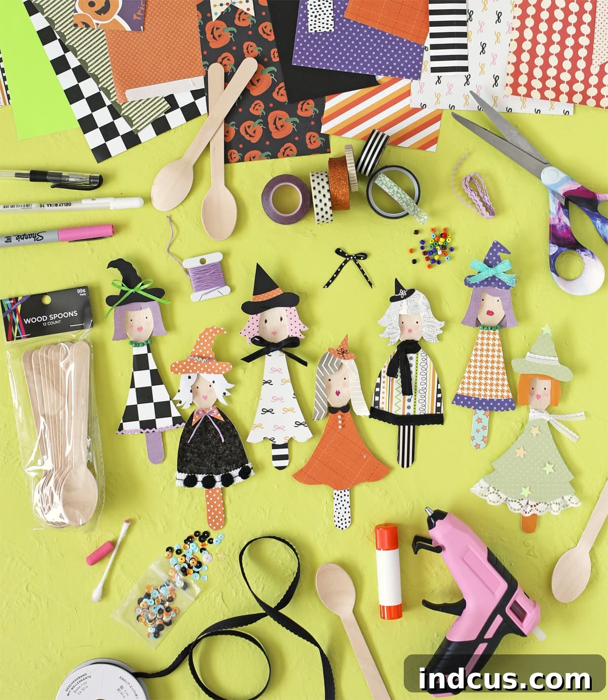 Materials needed for making wooden spoon witches, including spoons, paper, glue, and embellishments