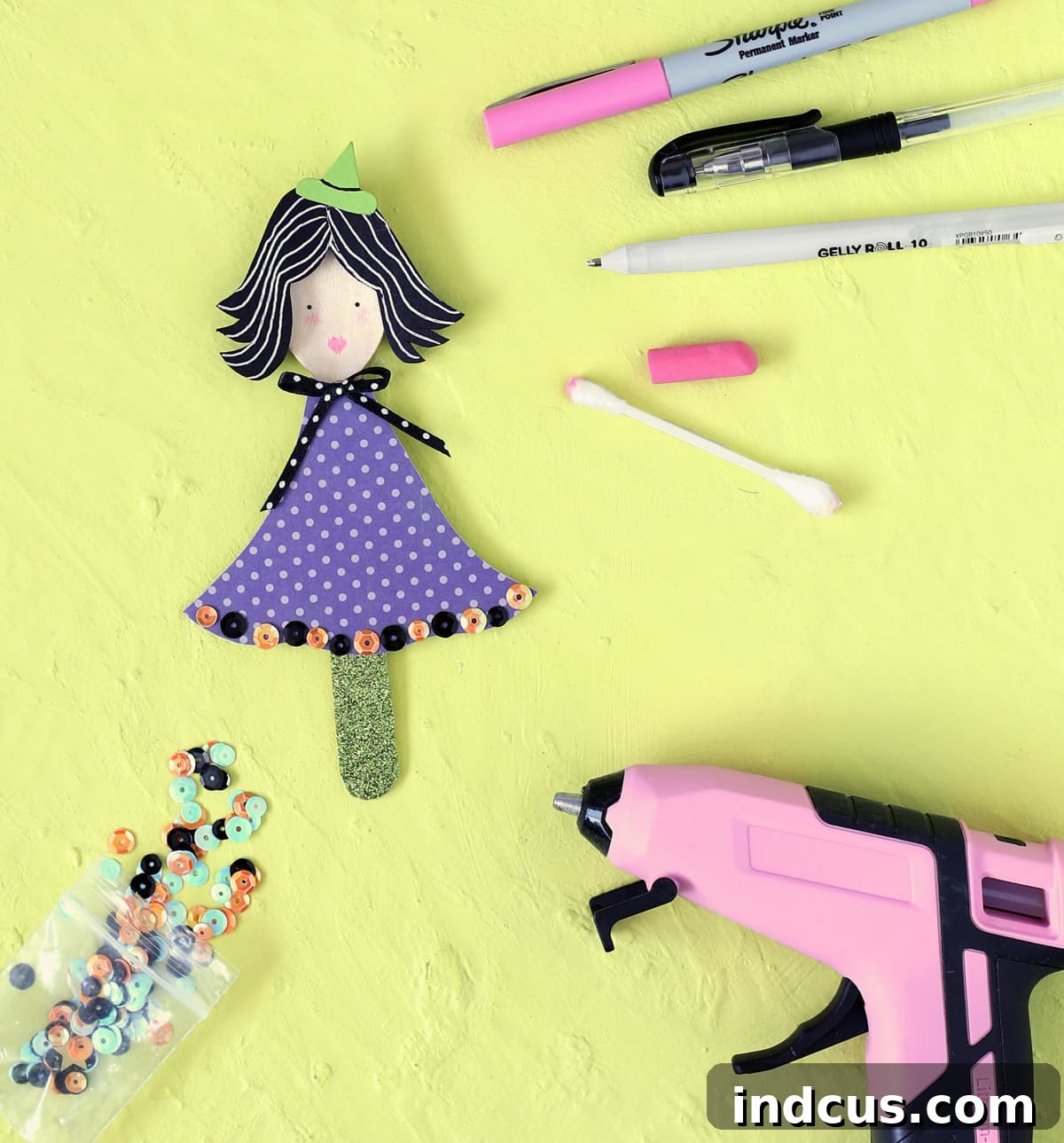 Adding embellishments and drawing a face with paint pens on a wooden spoon witch