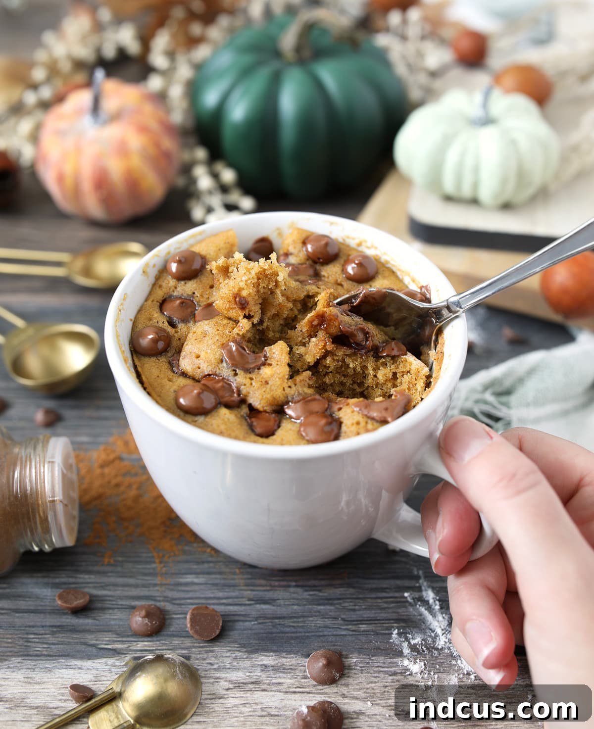 Single Serve Pumpkin Spice Cake 4 A top-down view of a pumpkin chocolate chip mug cake in a festive mug, with a spoon ready to dig in, emphasizing its appeal as a quick treat.