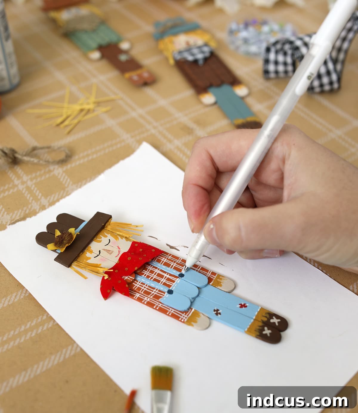 Adding details to a popsicle stick scarecrow with paint pens