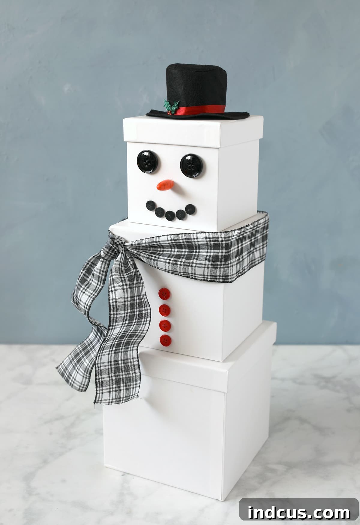 Completed reusable snowman gift tower made from stacked nested boxes, perfect for holiday gift giving and decor.