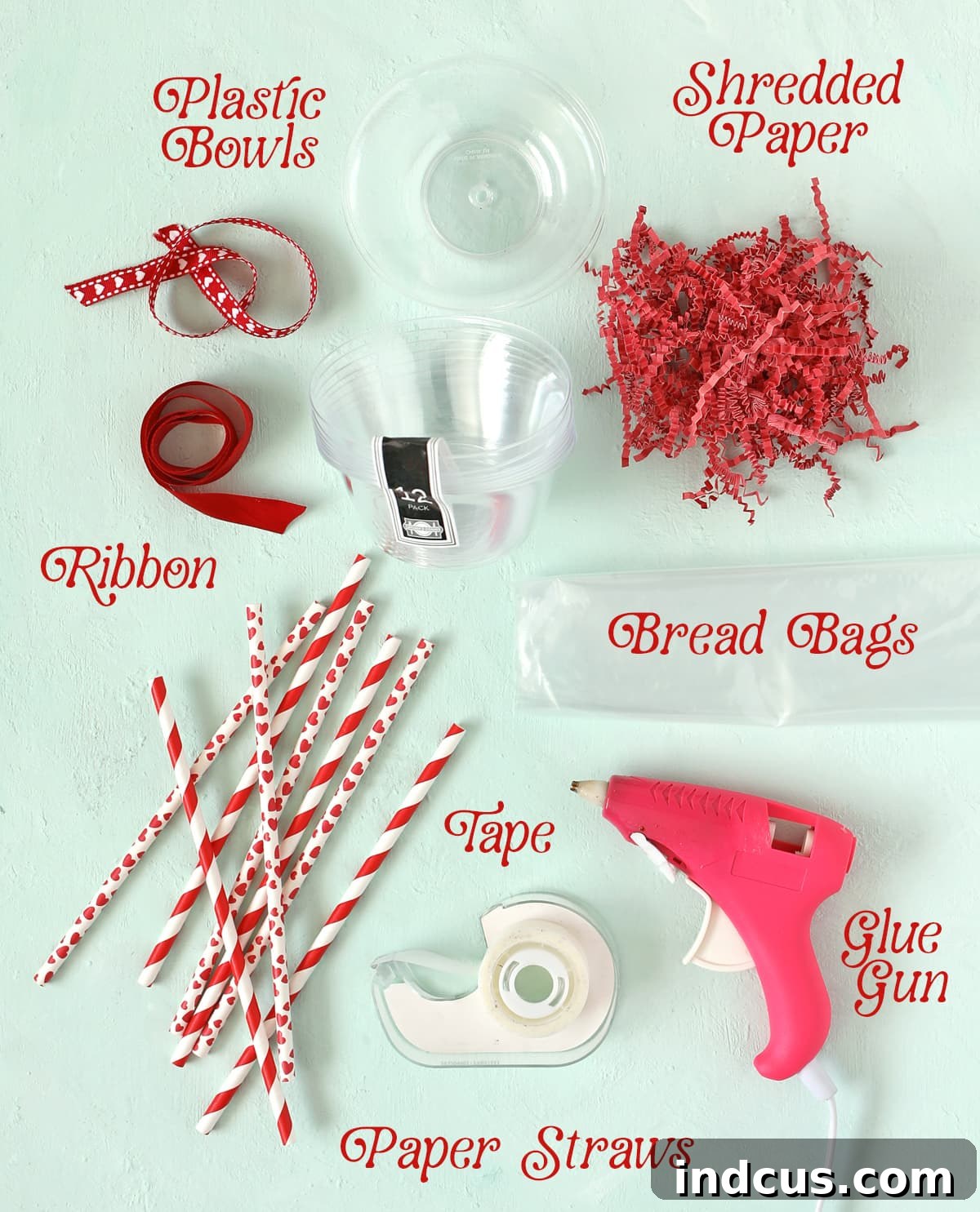 Essential materials for making DIY lollipop gifts, including clear plastic bowls, paper straws, plastic bags, ribbon, shredded paper, glue gun, and clear tape.