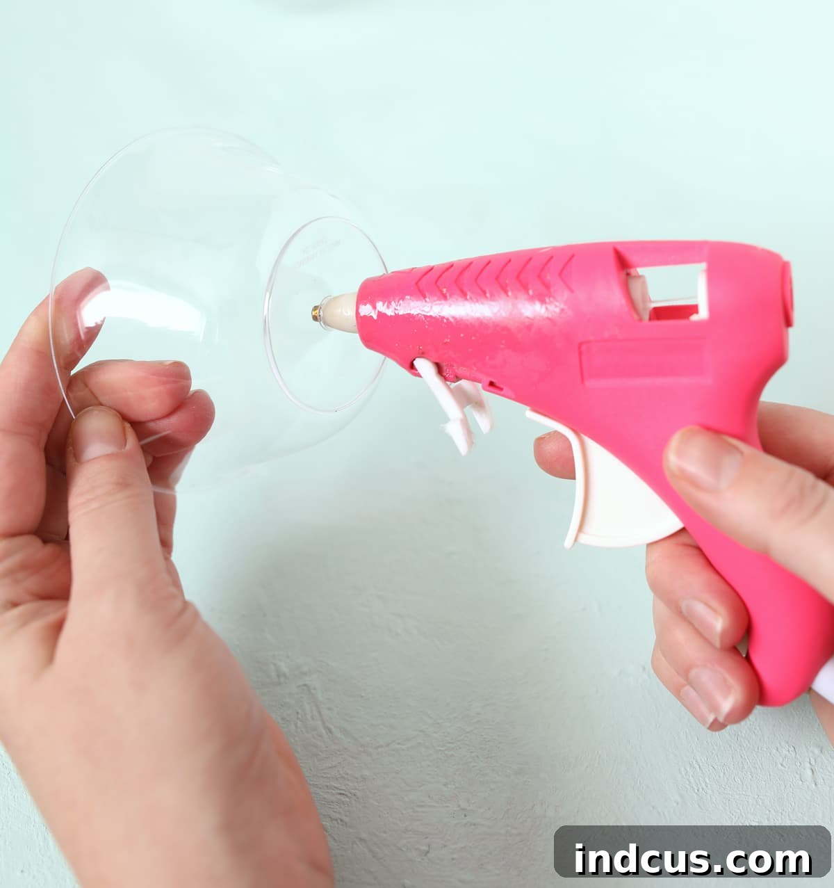 Melt a perfect hole in the center of a plastic bowl using a heated glue gun, preparing it for the lollipop stick.
