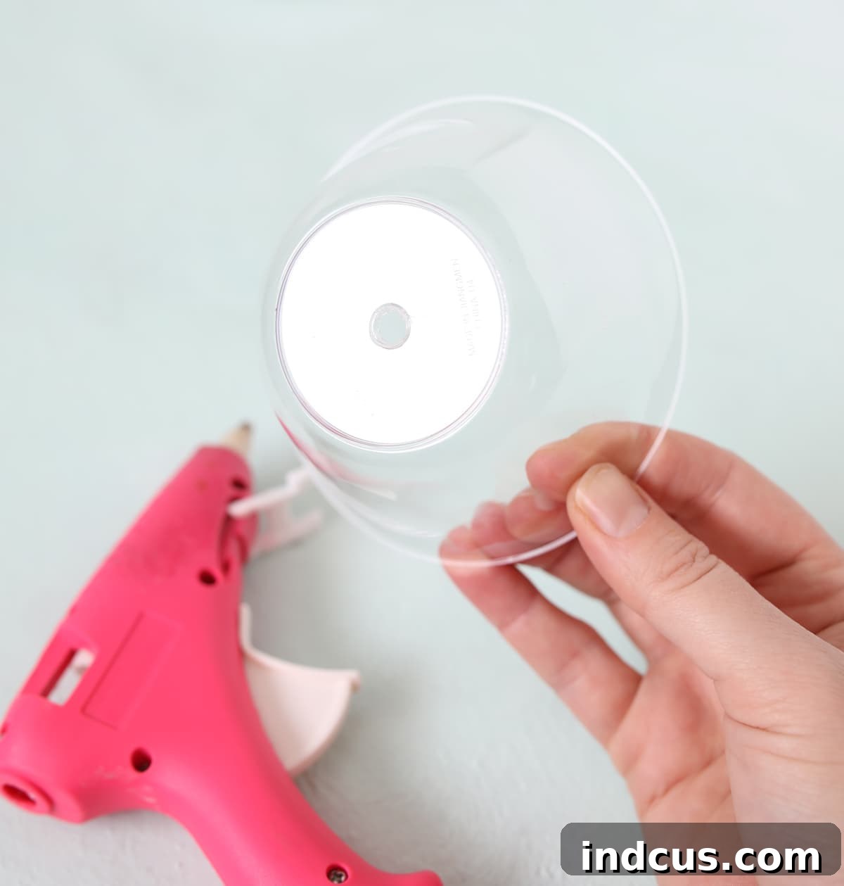Close-up view of a perfectly melted hole in a clear plastic bowl, ready for the paper straw insertion.
