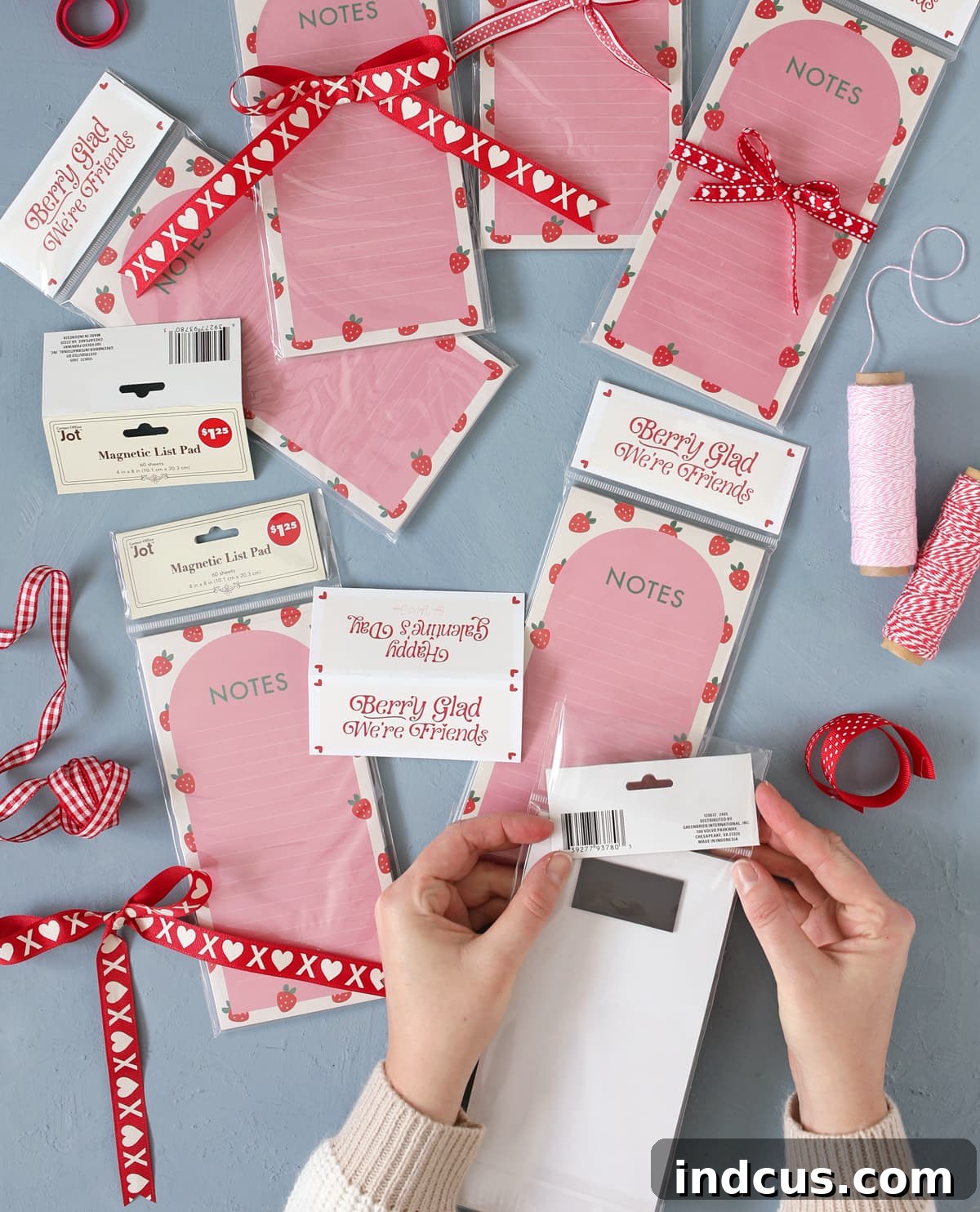 A creative dollar store hack showcasing a magnetic list pad with its original tag replaced by a custom, personalized design for gifting.