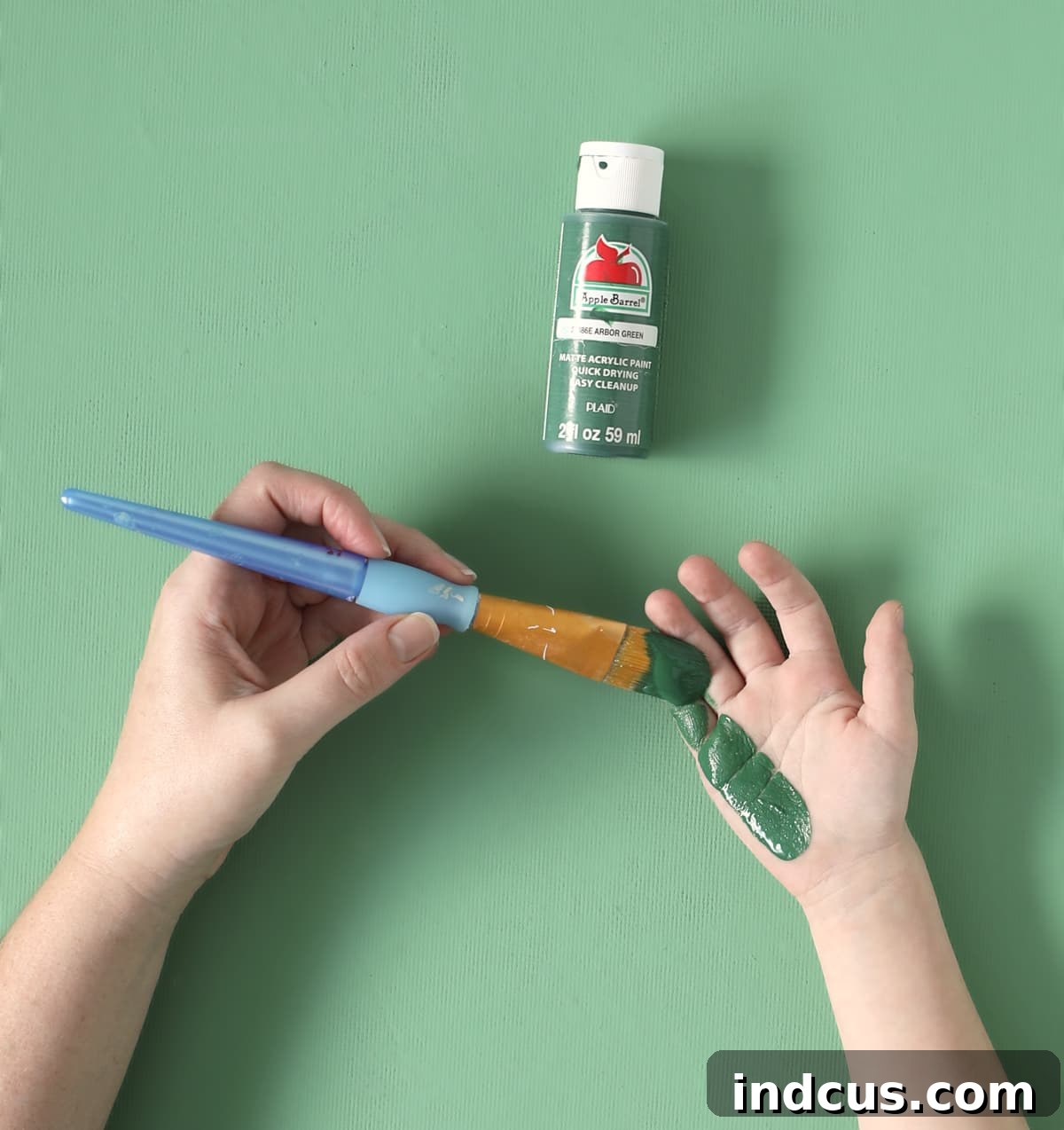 Applying green paint to a child's hand for the handprint craft