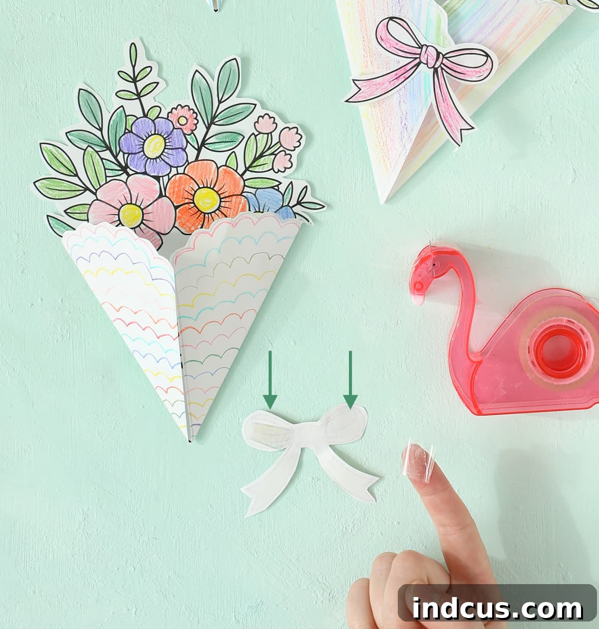 Detailed view of applying tape to the back of the bow, ready to secure the Mother's Day bouquet card closed.