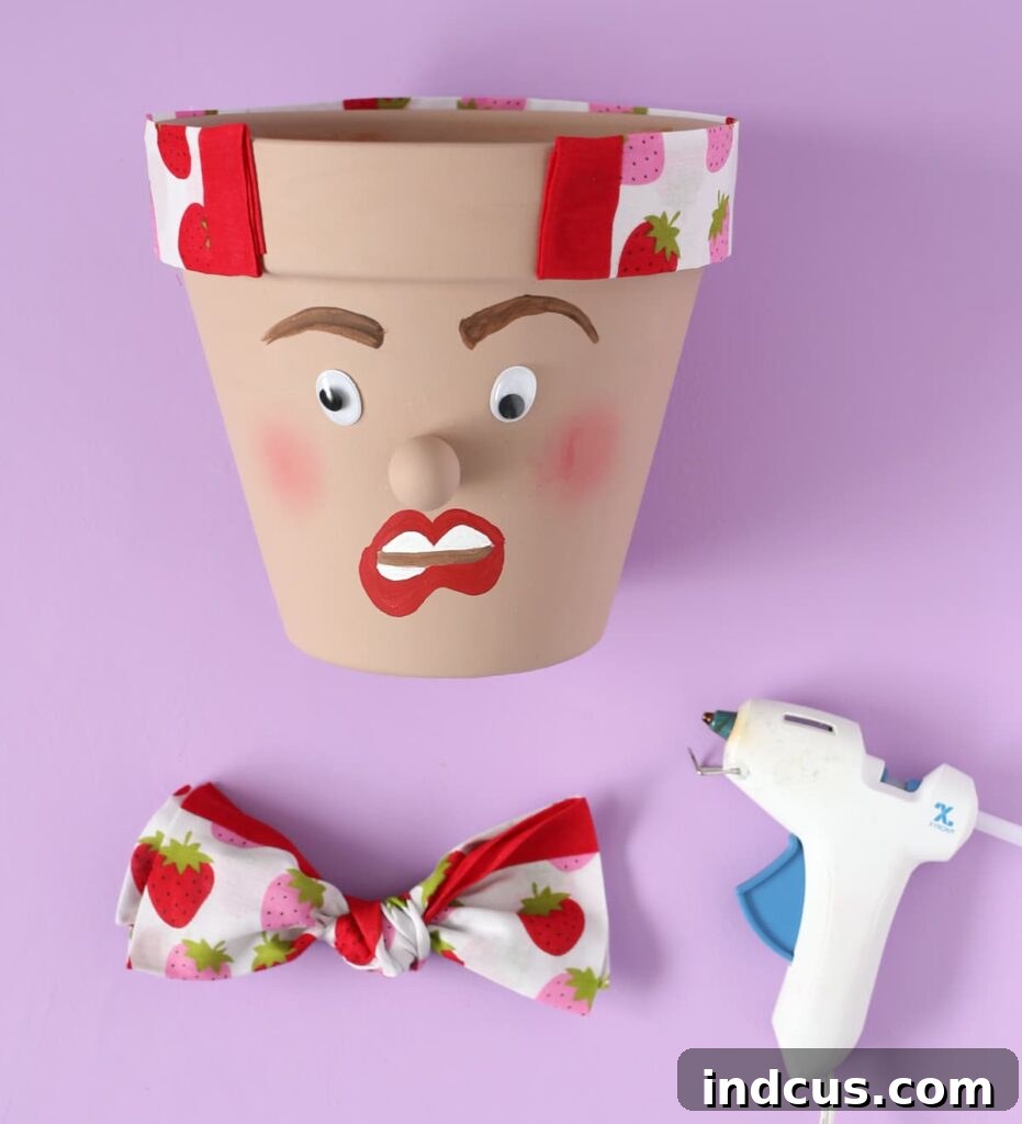 Attaching bandana hair wrap to pot head planter with hot glue