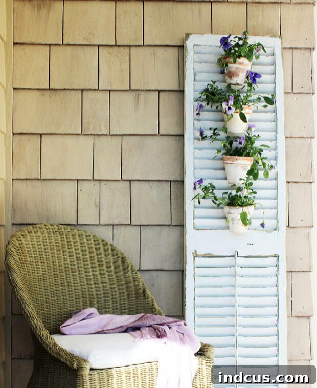 A repurposed old shutter turned into a charming DIY vertical planter with terracotta pots attached, ideal for a rustic garden aesthetic.