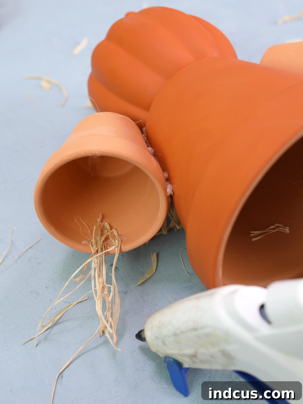 Craft Your Own Clay Pot Scarecrow 6 Gluing raffia to clay pot arms for a scarecrow craft