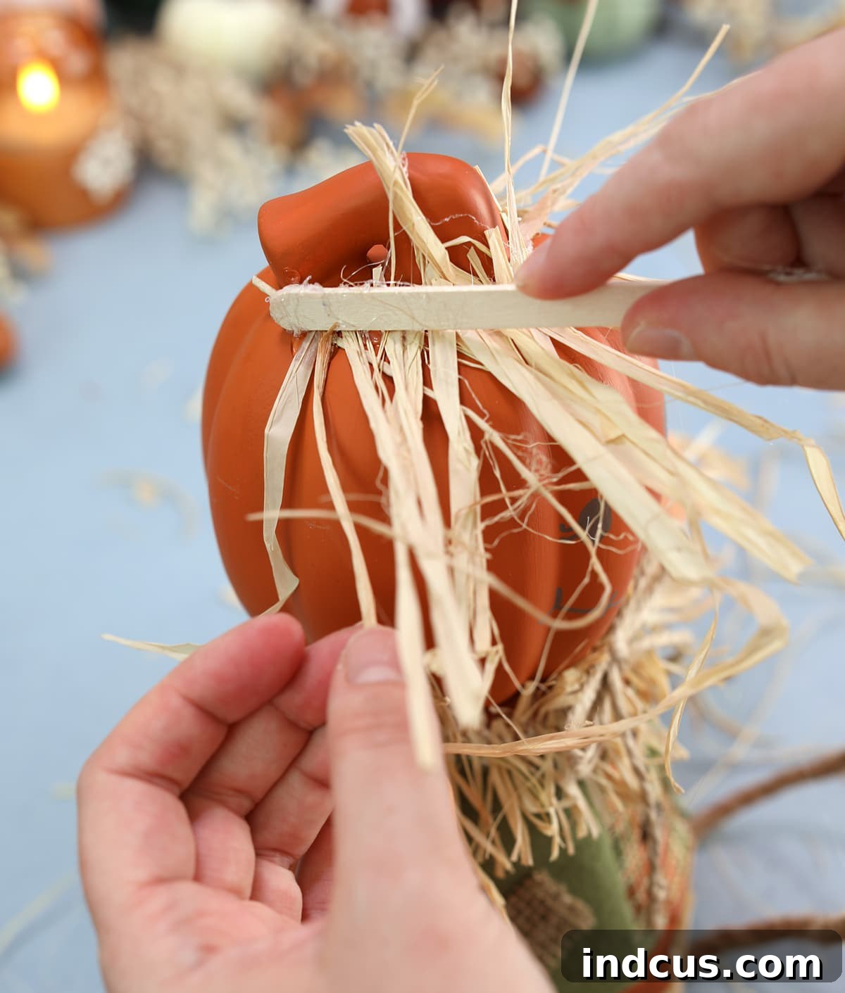 Craft Your Own Clay Pot Scarecrow 7 Adding hot glued raffia for scarecrow hair and body accents