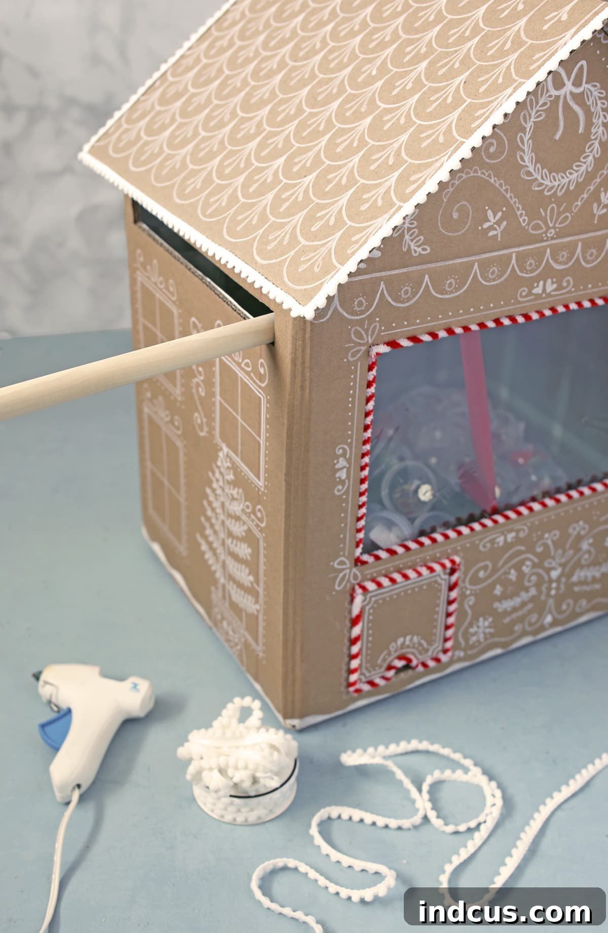 glue pom pom trim to gingerbread house roof