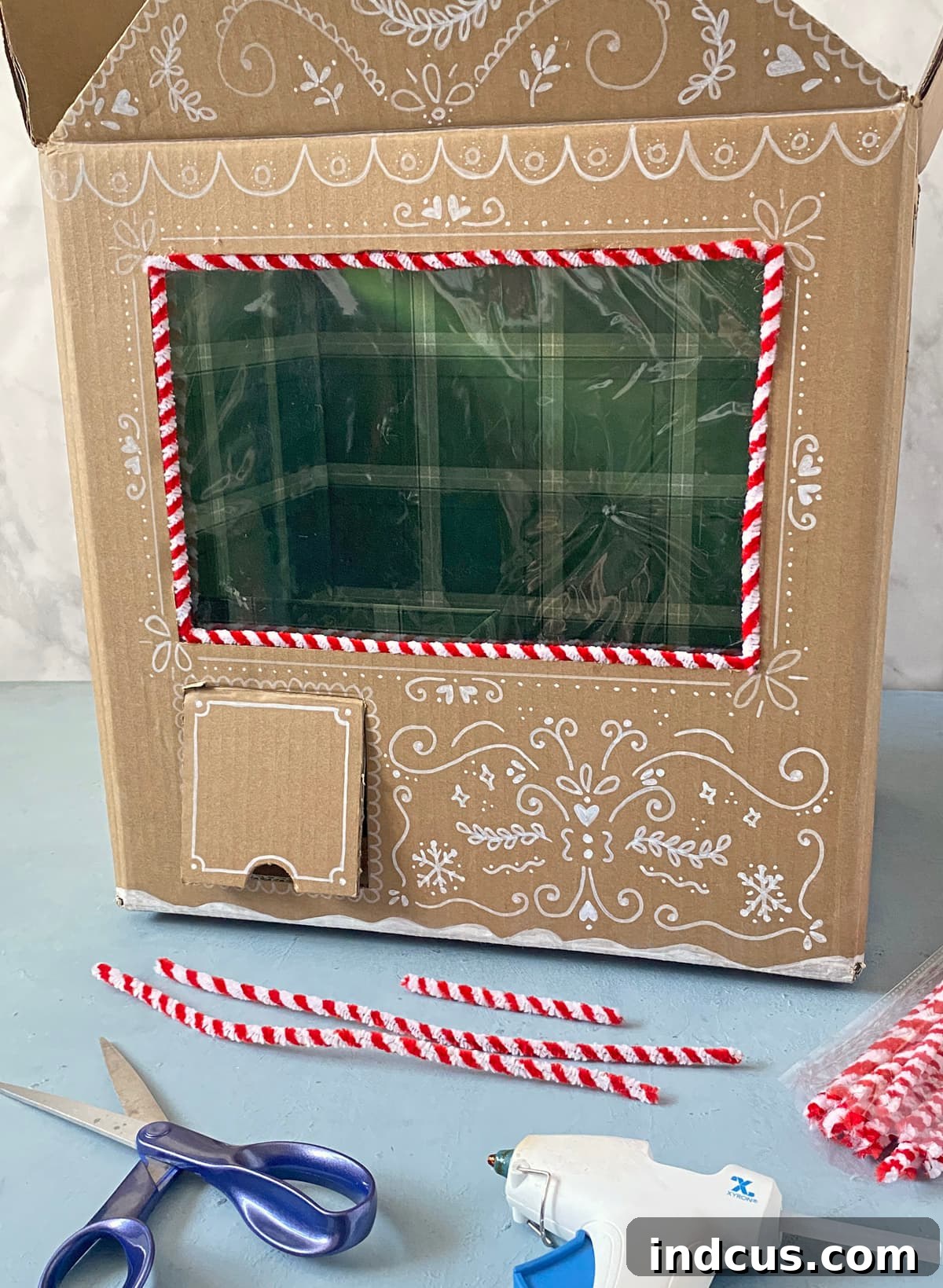 candy cane chenille stems to trim out a cardboard gingerbread house claw machine
