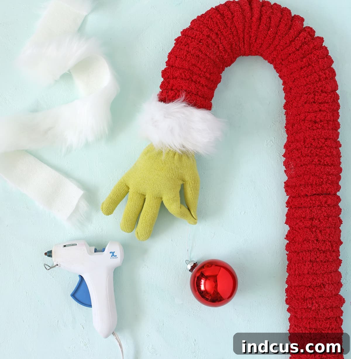 A close-up shot of the white faux fur trim being glued around the cuff of the green Grinch hand.
