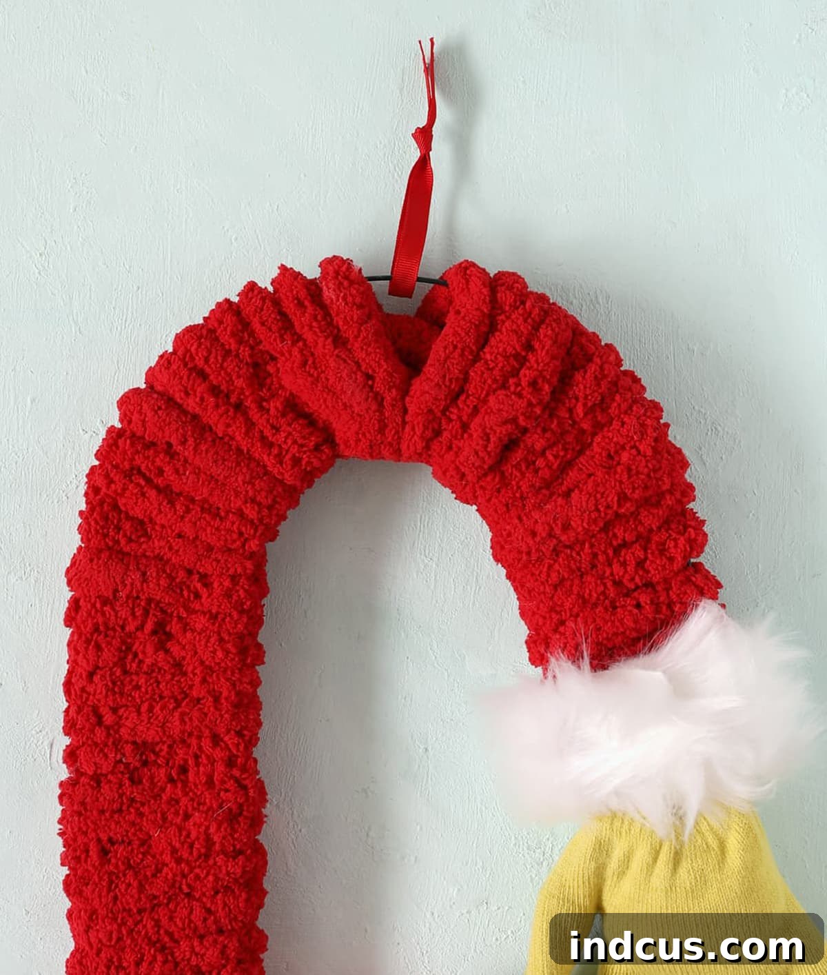 A small red ribbon loop tied to the top of the candy cane form for hanging the Grinch decoration.