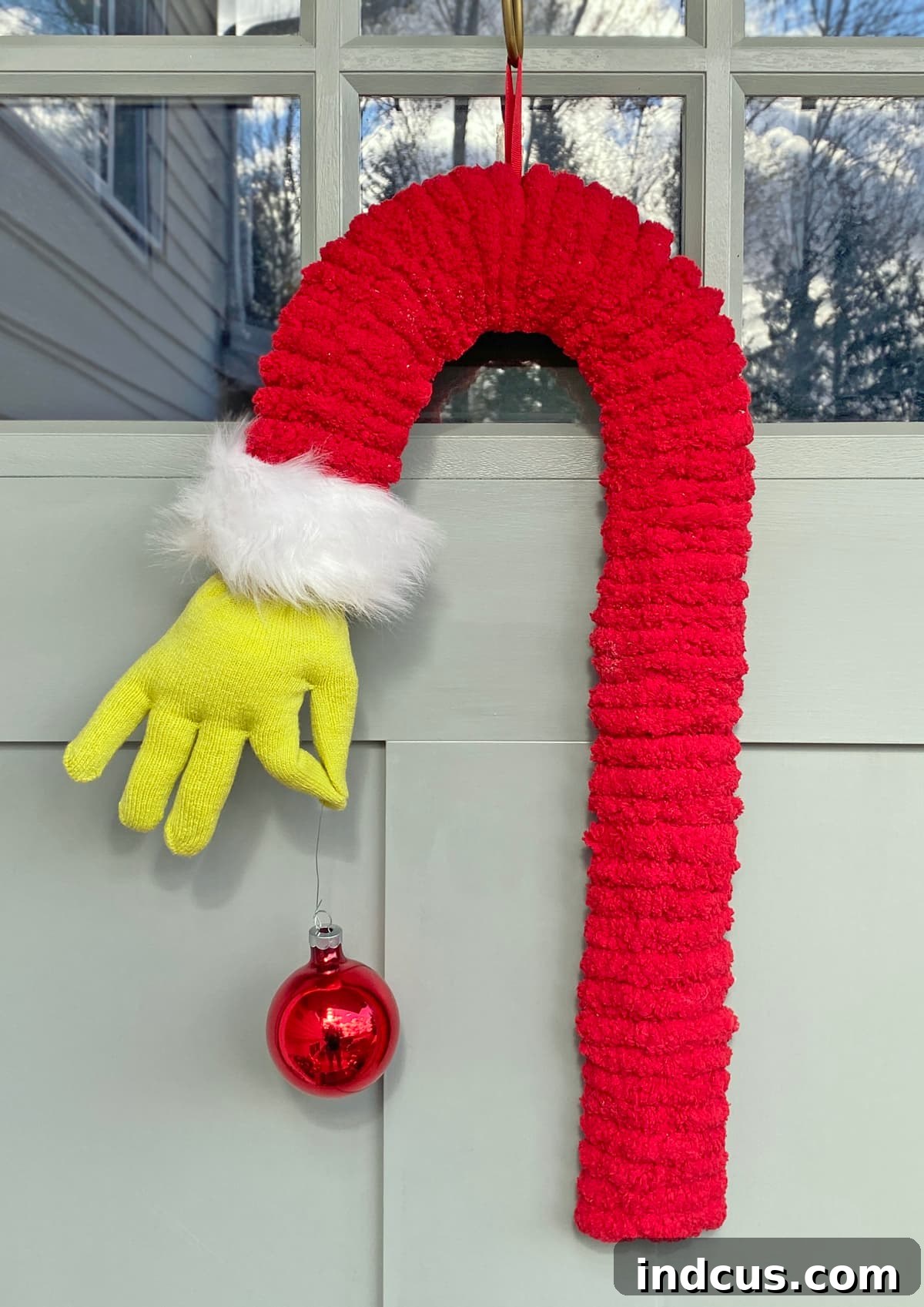 The completed Grinch hand door decoration, hanging gracefully on a white door, ready for the holidays.