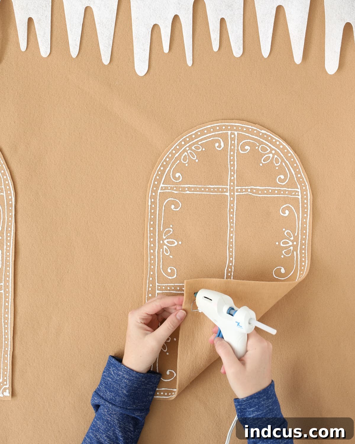 making a felt gingerbread house by attaching decorated windows