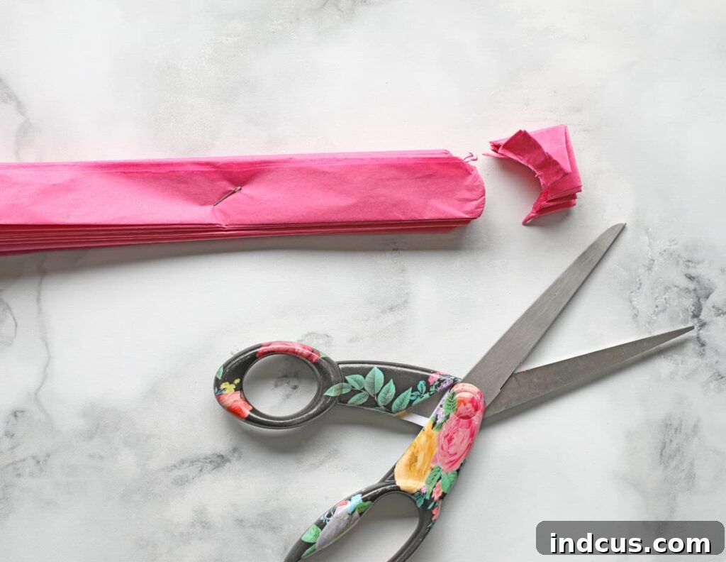 Crafting Delicate Tissue Paper Blooms: A Full Guide 5 Scissors cutting the ends of the folded tissue paper into rounded petal shapes.