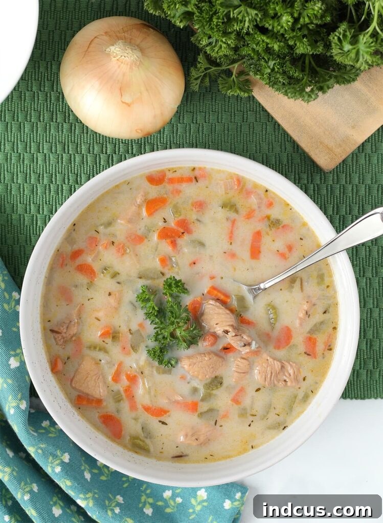 A close-up of a spoon dipping into a bowl of easy chicken and wild rice soup, showing its creamy texture.