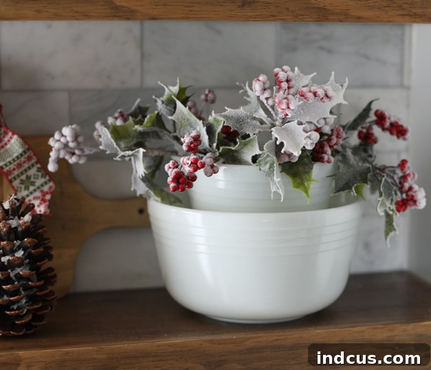 Decorating the kitchen for Christmas, showcasing vintage Pyrex bowls adorned with frosted holly berry sprigs.